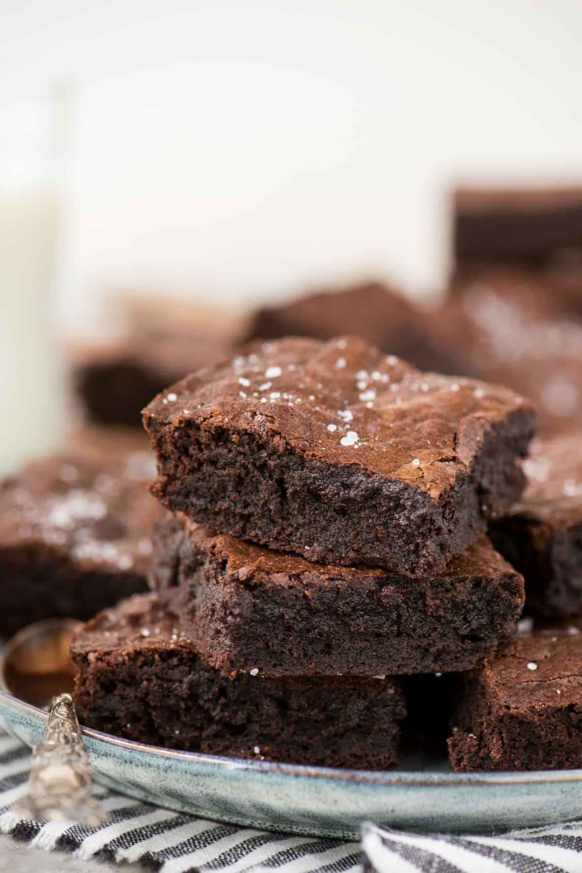 homemade brownies stacked in a tower on light blue plate with white background 