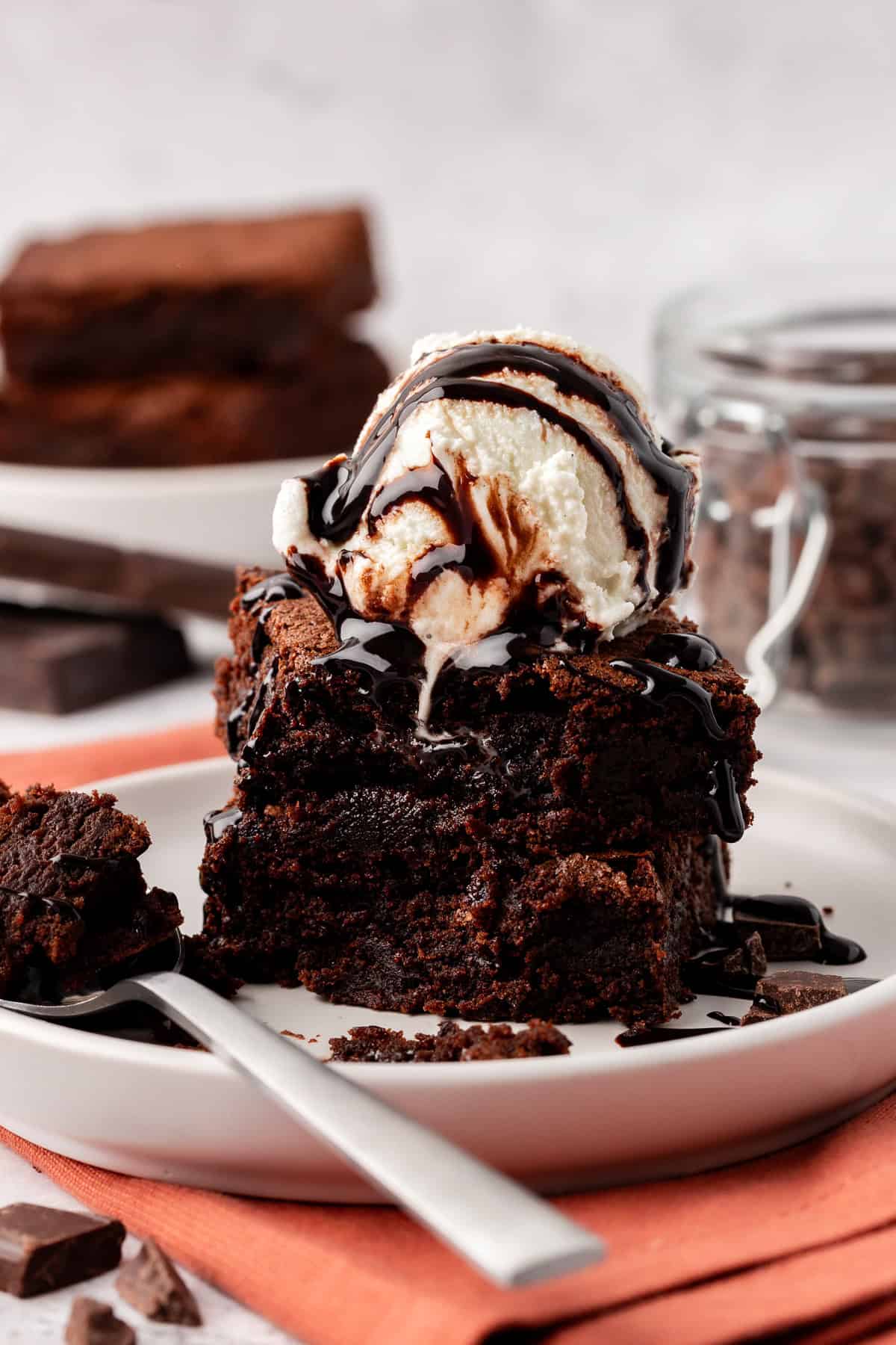 2 brownies stacked topped with ice cream on white background