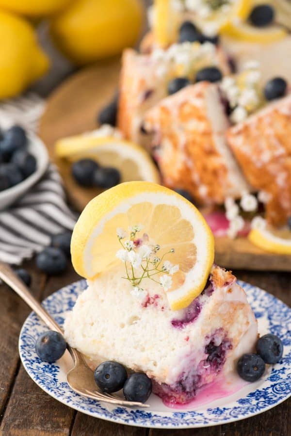 Slice of lemon blueberry angel food cake on blue and white floral plate on wood background.