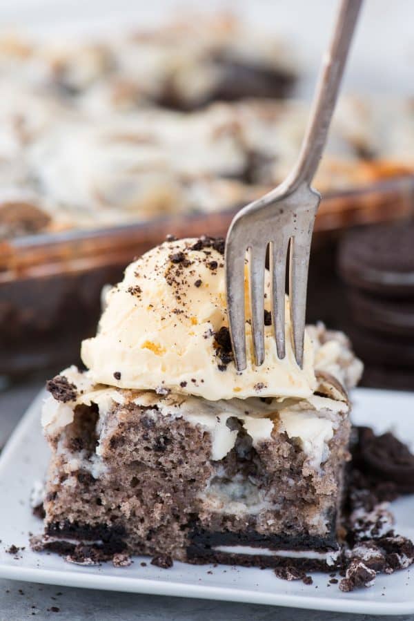 This oreo earthquake cake is a white cake mix loaded with whole oreos and oreo crumbs. Swirl in the cream cheese frosting layer and it bakes into the cake creating frosting filled crevices and cracks on top of the cake. #earthquakecake #oreocake #cake slice of oreo earthquake cake with scoop of vanilla ice cream on top on with fork going into the cake