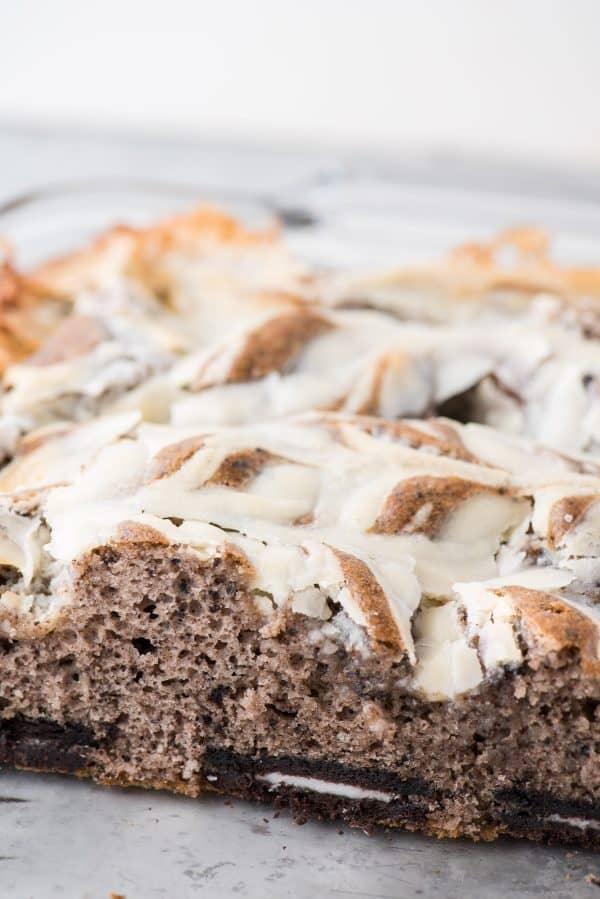 This oreo earthquake cake is a white cake mix loaded with whole oreos and oreo crumbs. Swirl in the cream cheese frosting layer and it bakes into the cake creating frosting filled crevices and cracks on top of the cake. #earthquakecake #oreocake #cake side shot of oreo earthquake cake in glass pan