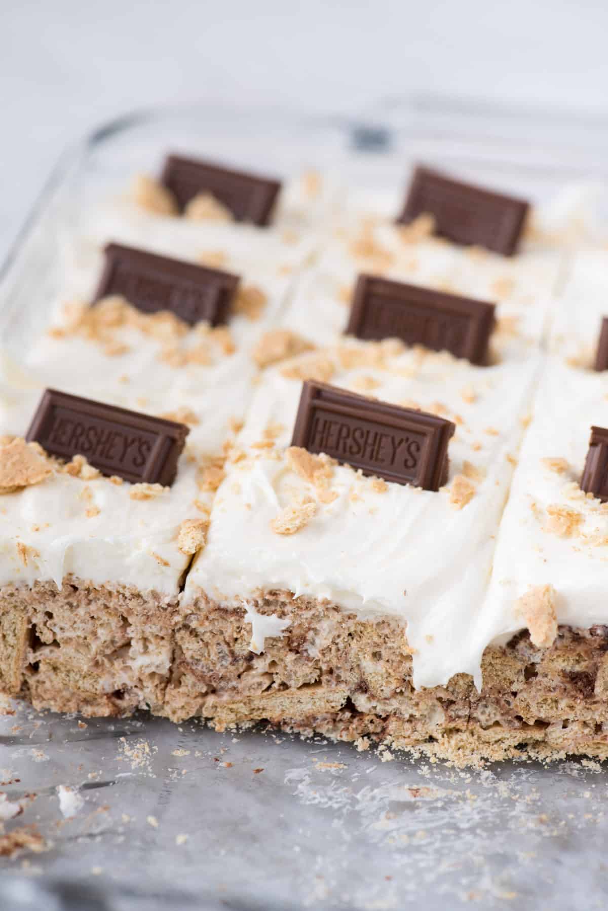 S’mores bars with marshmallow frosting and hershey’s chocolate bars in glass 9x13 inch pan