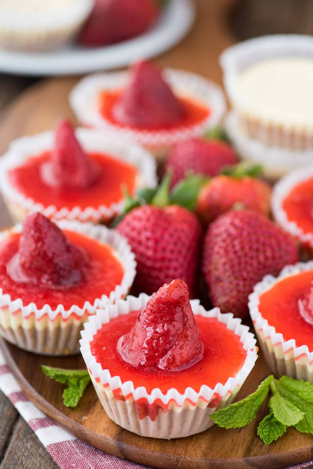 mini plain cheesecakes with strawberry topping on wood serving tray
