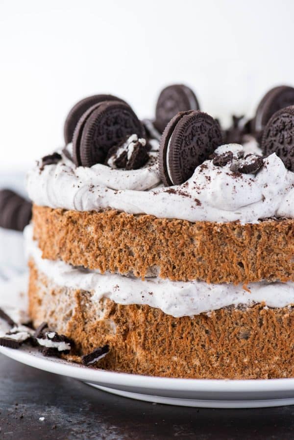 oreo angel food cake with oreo whipped cream and crushed oreo pieces on white plate on dark background