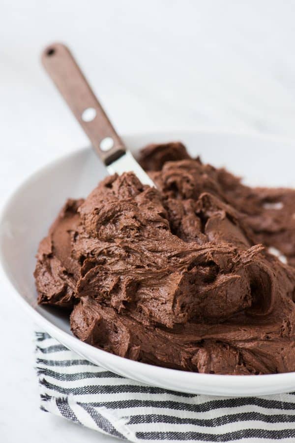 chocolate frosting in white bowl with striped towel