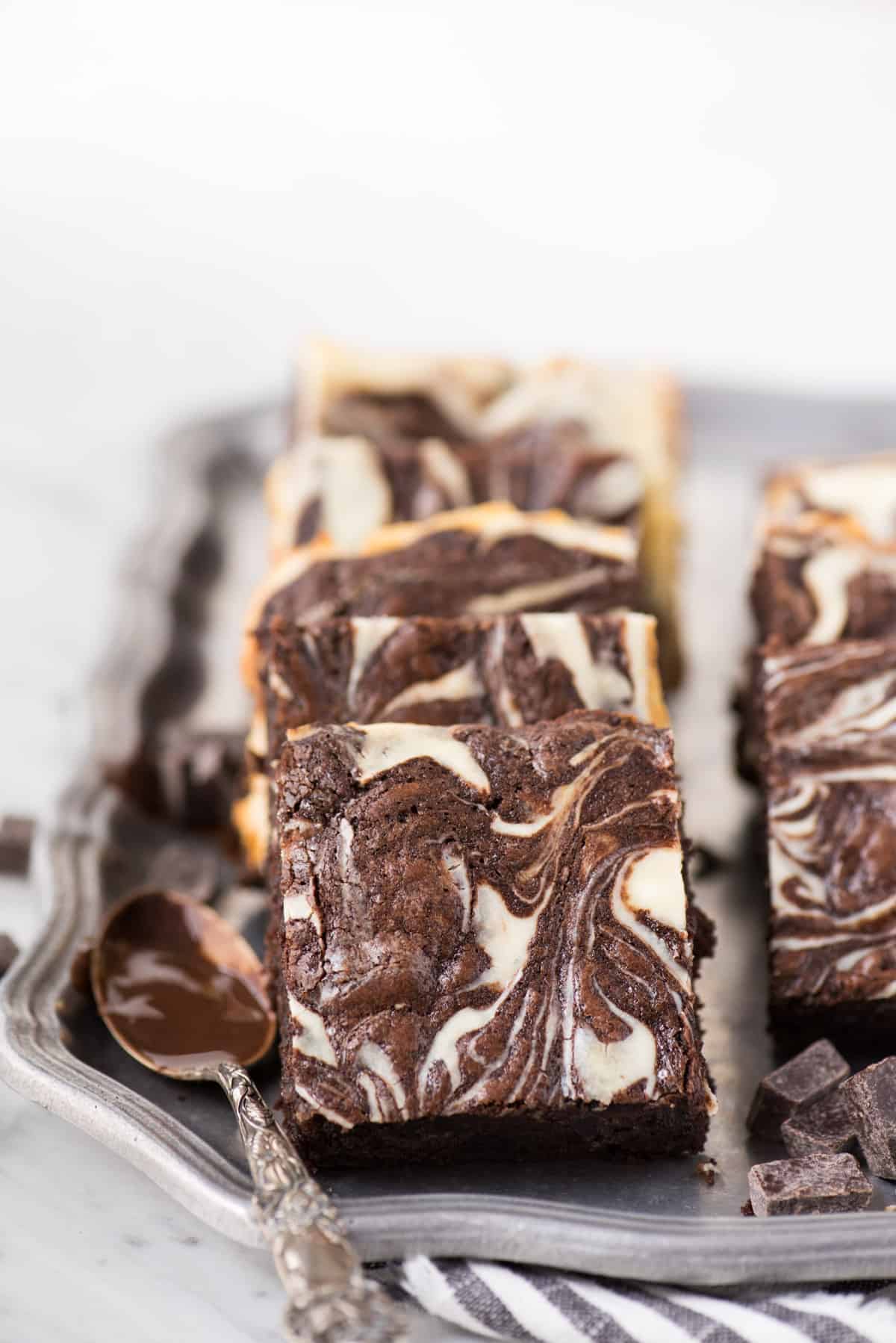 cream cheese swirl brownies in a line on metal serving tray