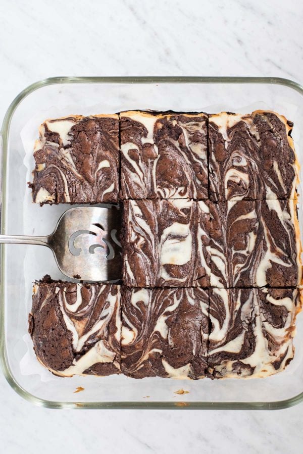 cream cheese swirl brownies cut into squares in glass pan