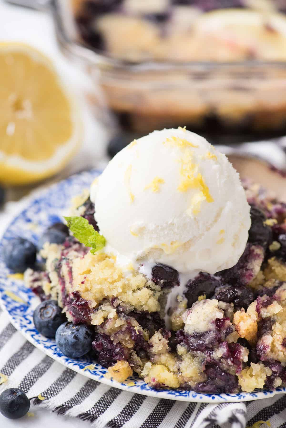 lemon blueberry dump cake on blue floral plate with scoop of vanilla ice cream on top
