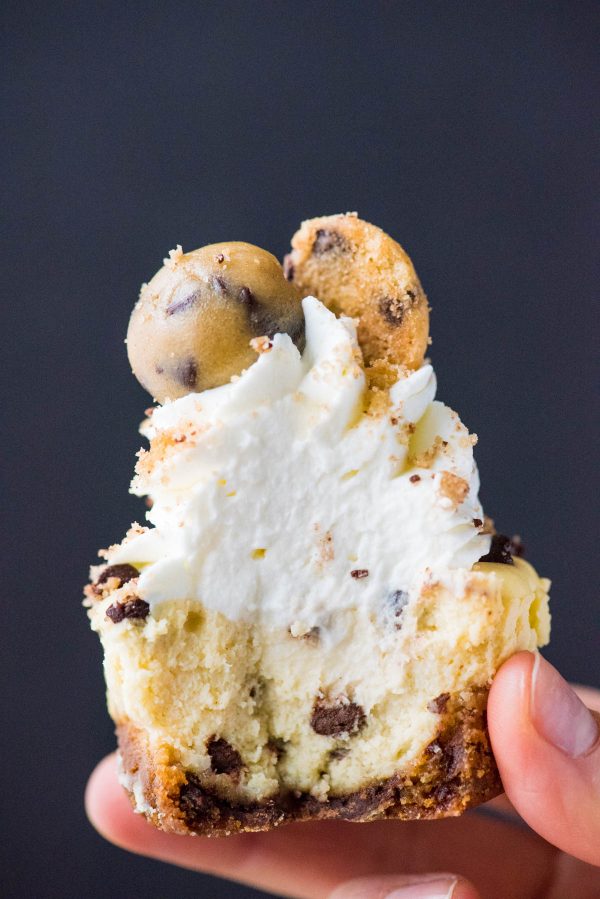 close up of hand holding mini chocolate chip cookie dough cheesecake with bite removed