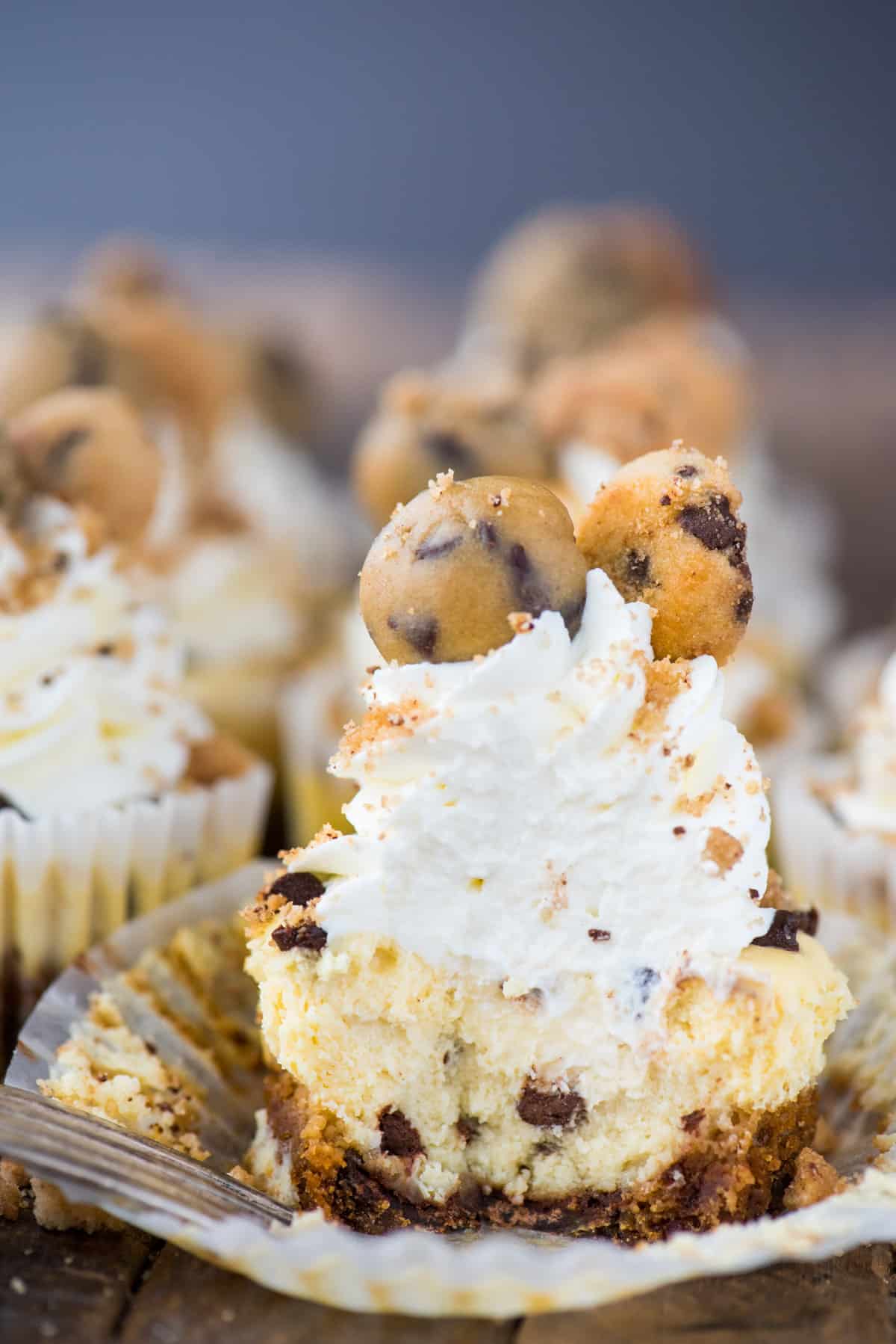 mini chocolate chip cookie dough cheesecake with bite removed on wood background 