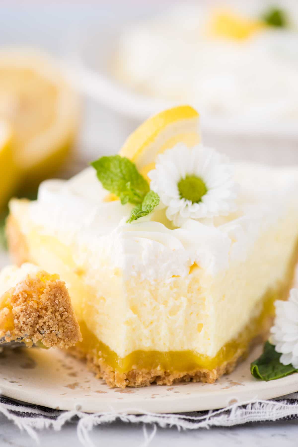a slice of no bake triple layer lemon pudding pie on white plate with bite removed