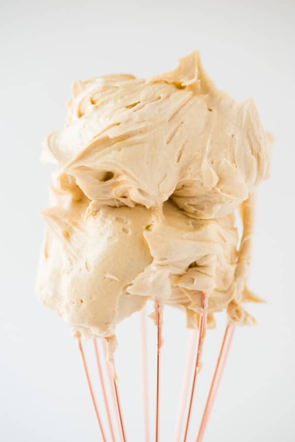 peanut butter frosting on rose gold whisk with white background