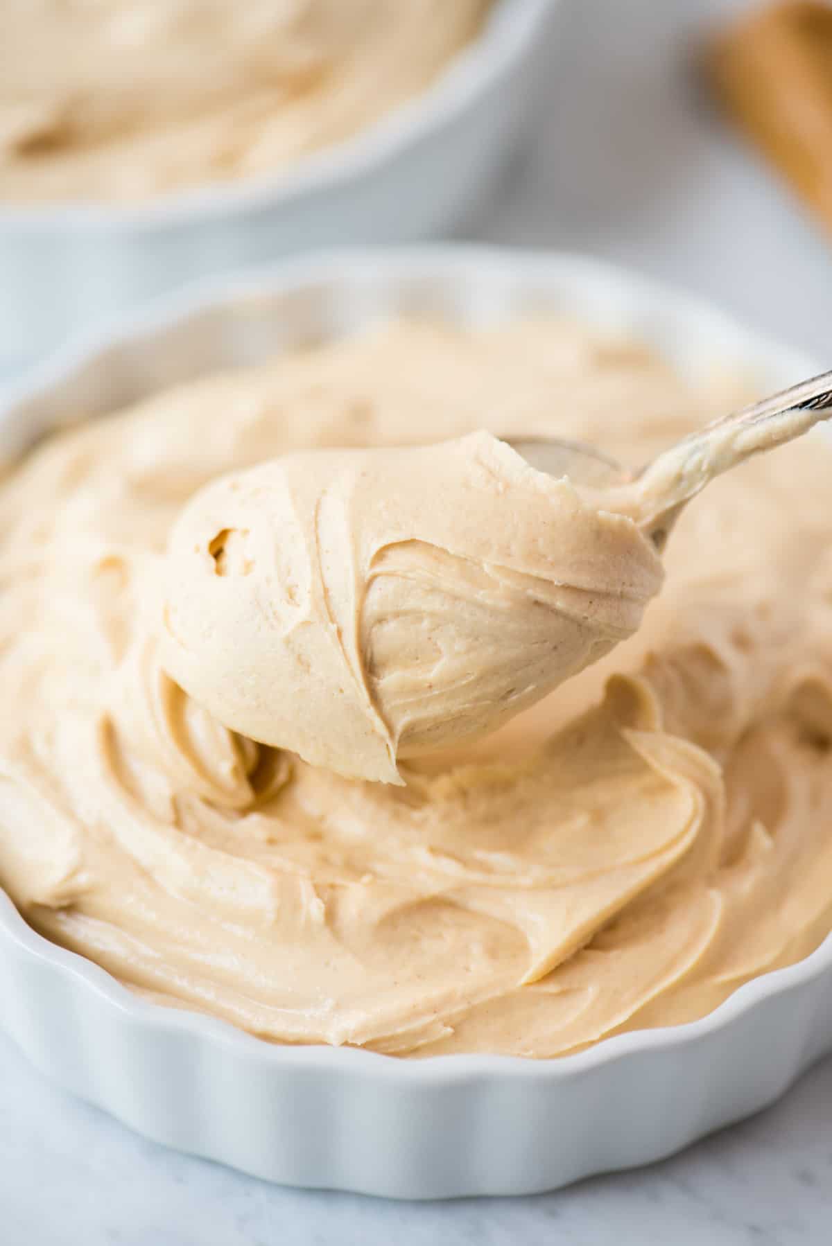 peanut butter frosting in white bowl with spoon