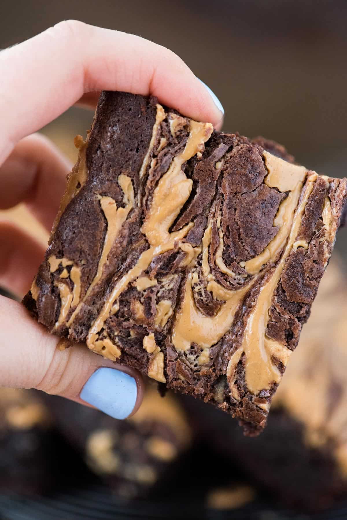 close up of fingers holding a peanut butter swirl brownie