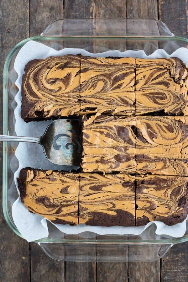 peanut butter swirl brownies cut into squares in glass pan on dark background