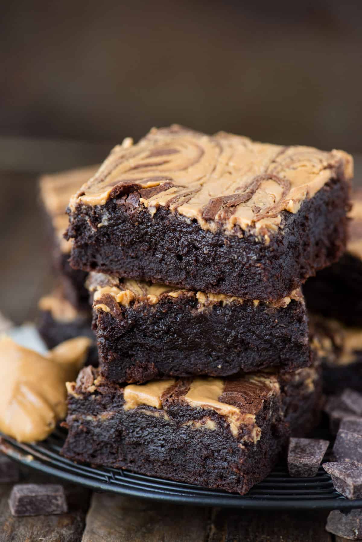 3 peanut butter swirl brownies stacked on each other on dark background