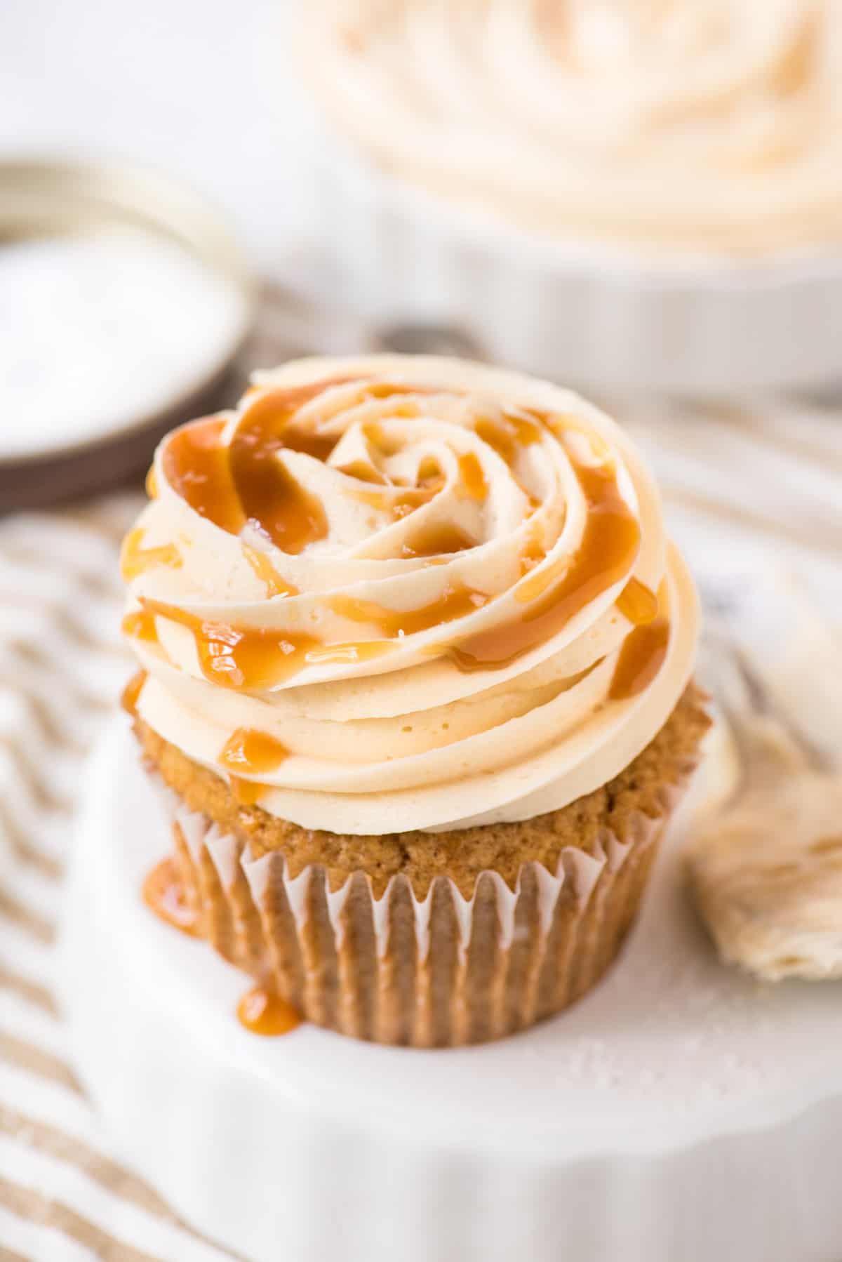 salted caramel frosting piped on cupcake on white background