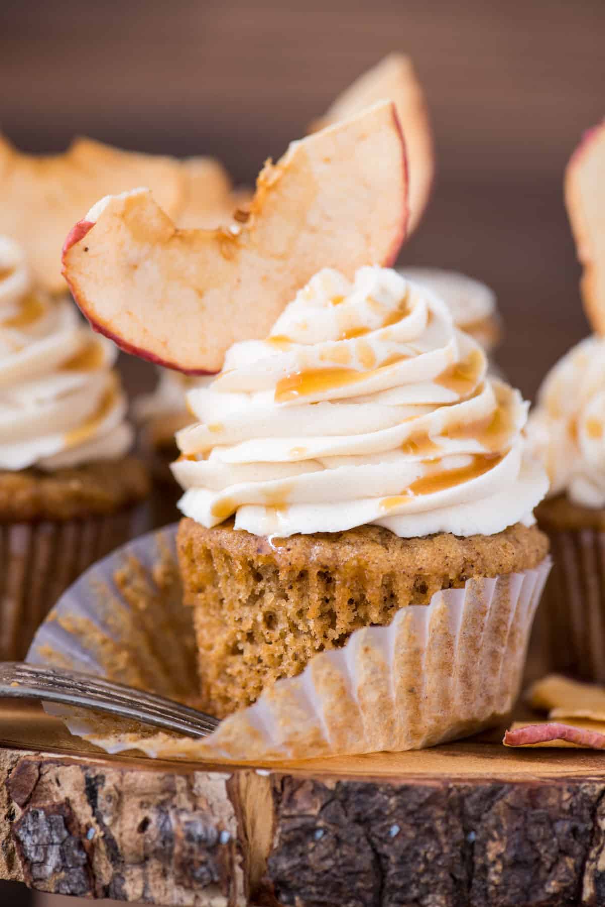 apple spice cupcake with caramel frosting and apple chip on wood cake stand with wood background 