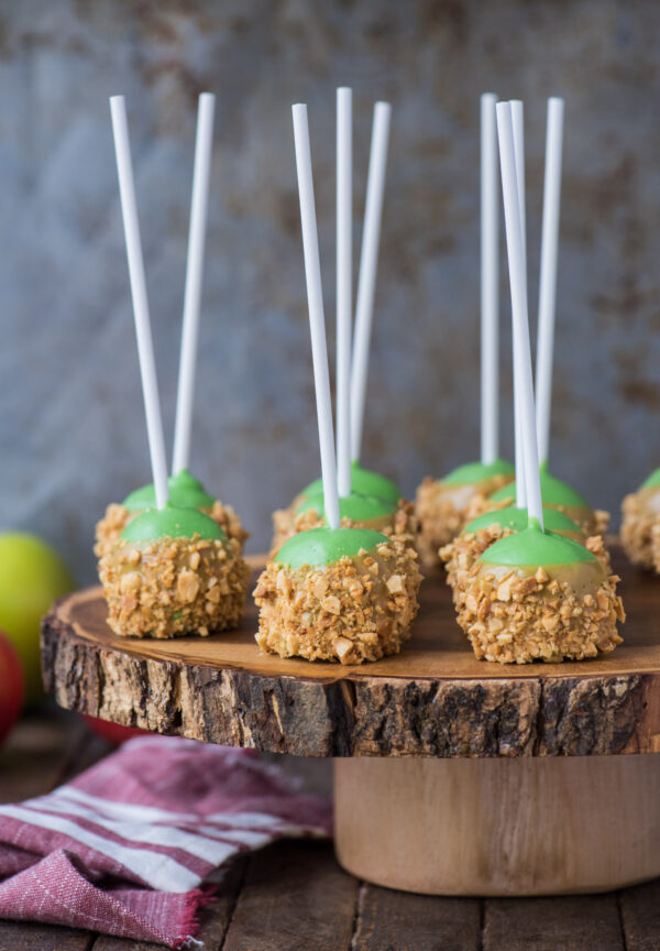 oreo balls that look like caramel apples on round wooden stand with metal background