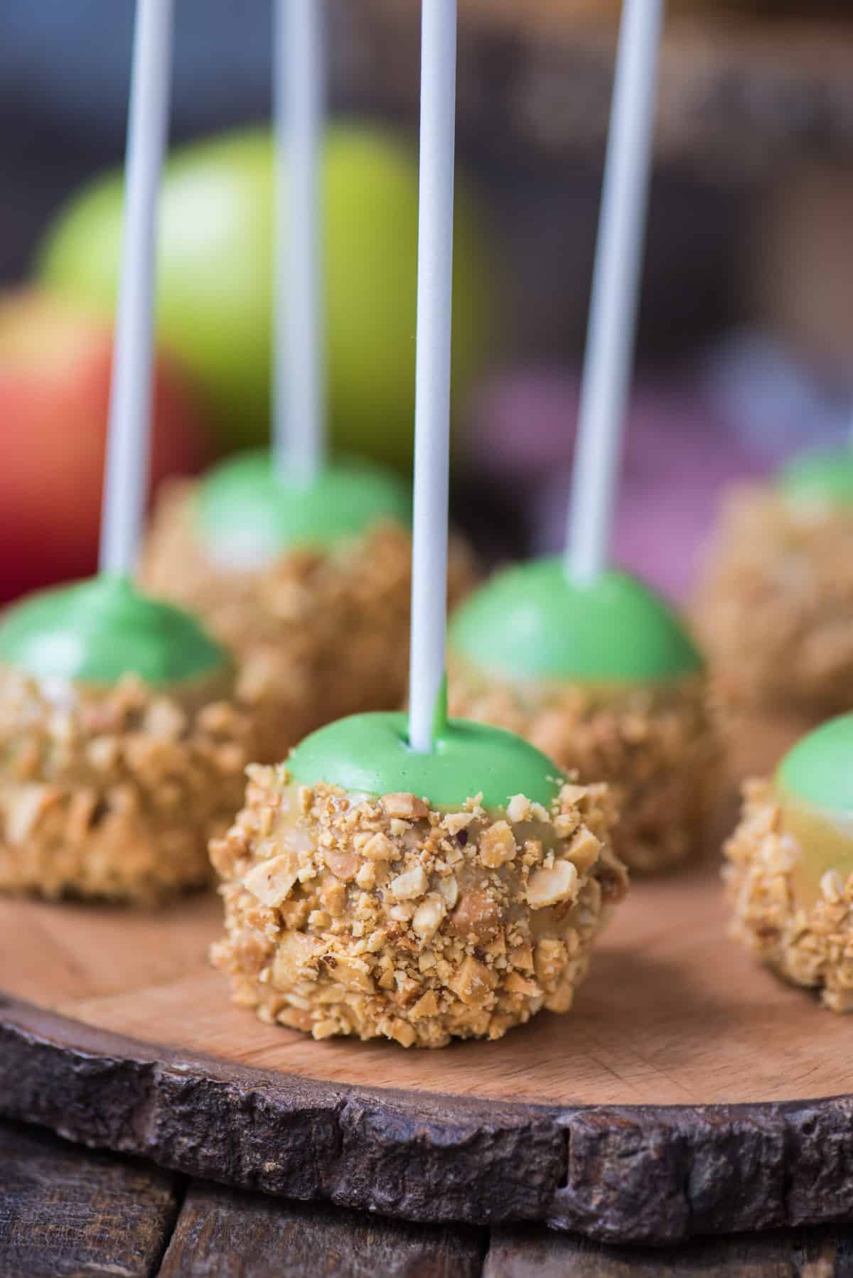 oreo balls that look like caramel apples on round wooden stand with apples in the background