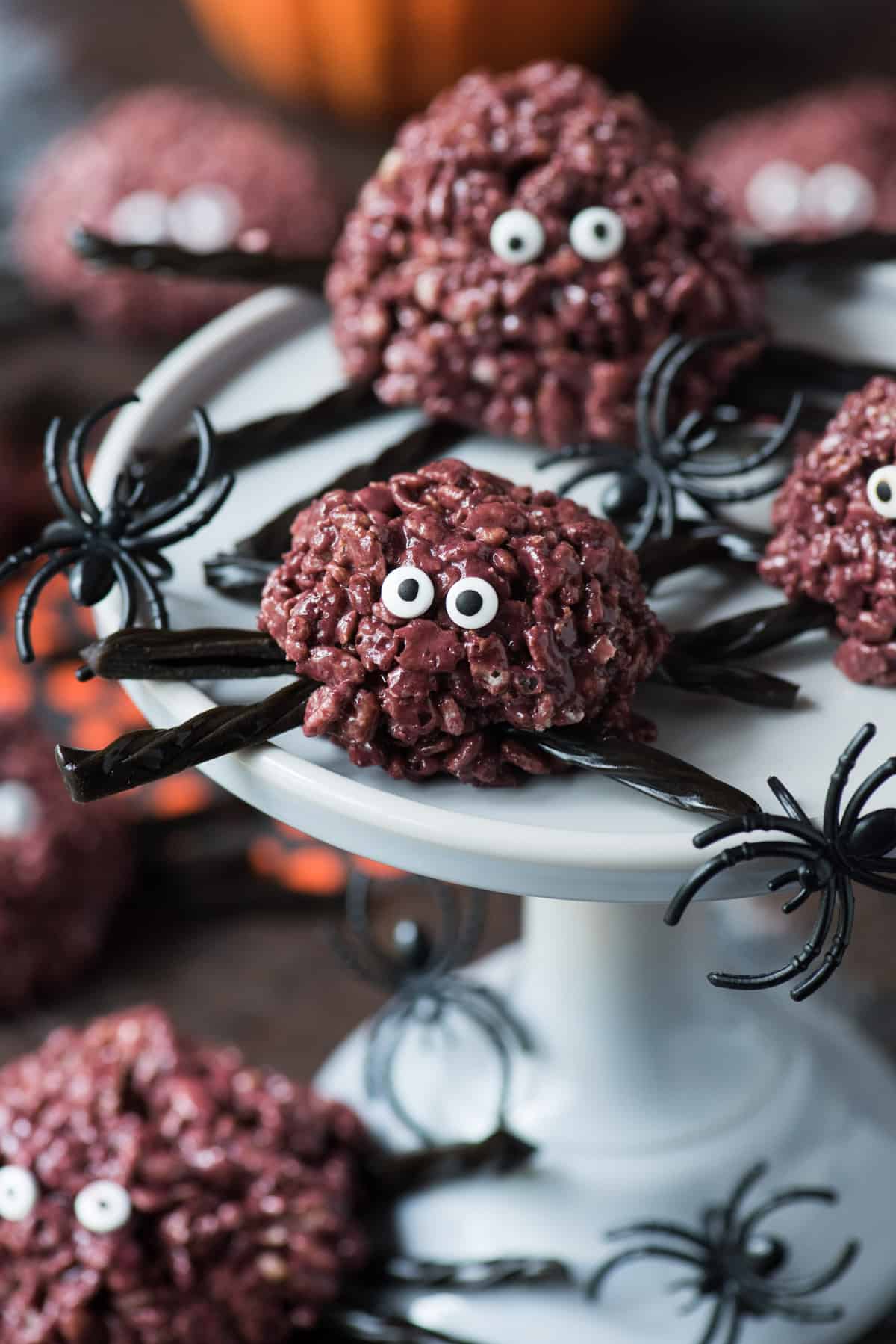 purple spider rice krispie treats with black licorice legs on a gray serving stand 