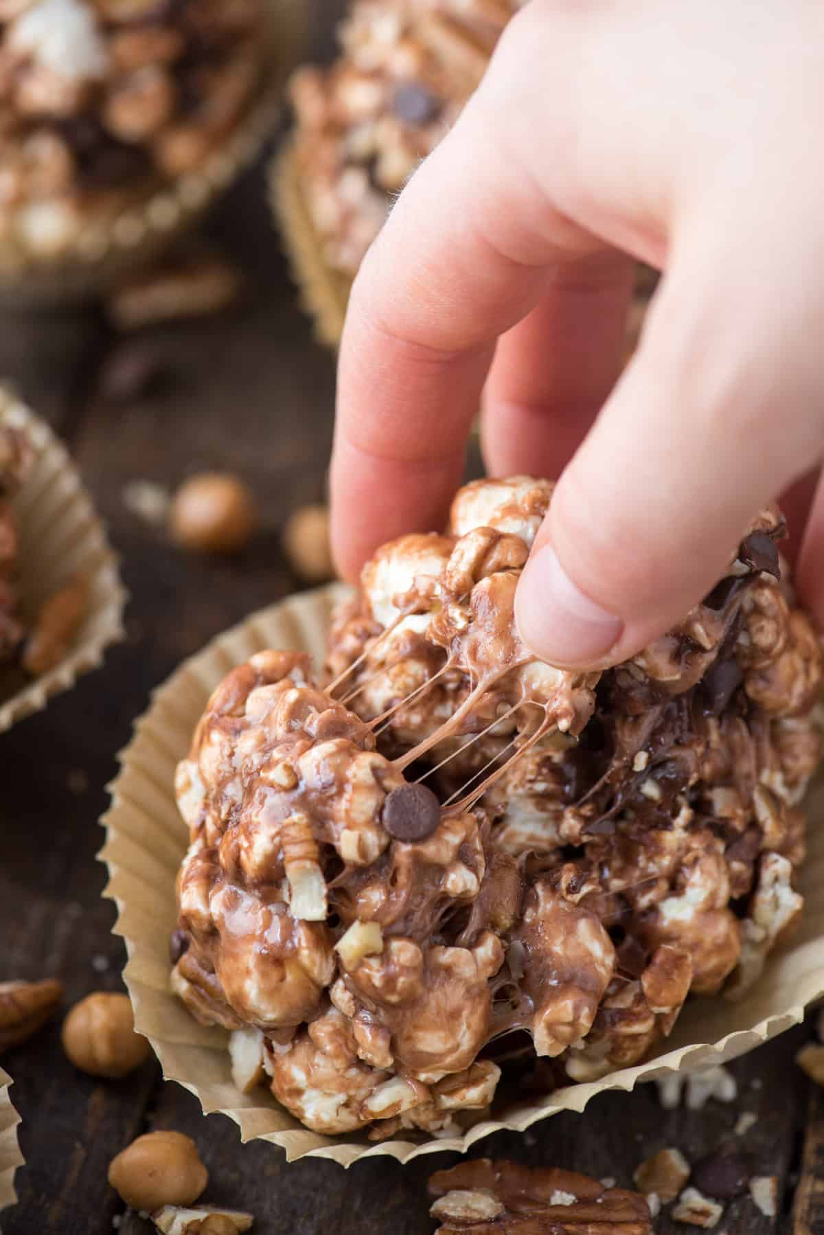 turtle popcorn ball with caramel, chocolate and pecans with hand in the picture