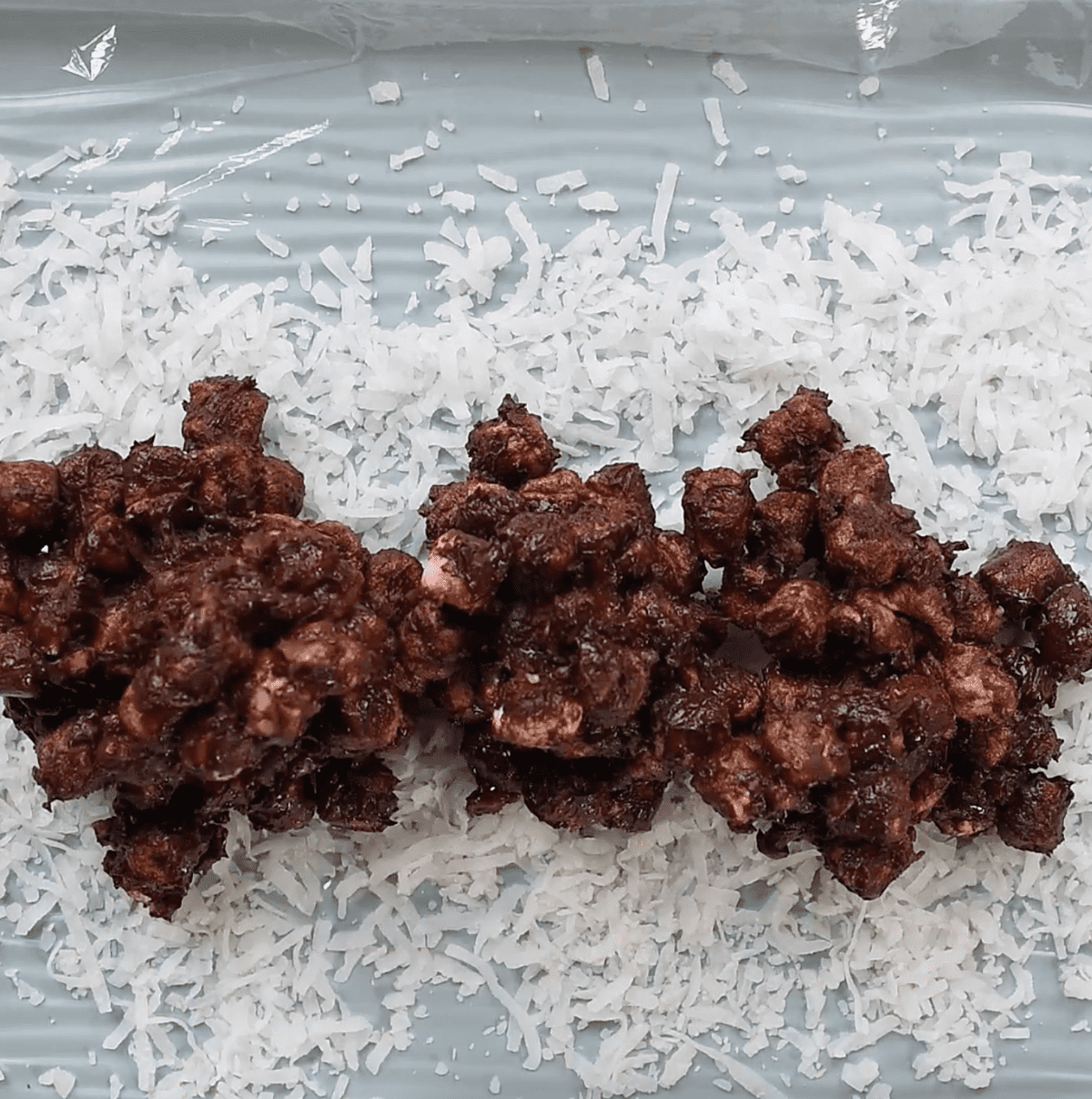 shredded coconut and chocolate marshmallows mixture spread over plastic wrap