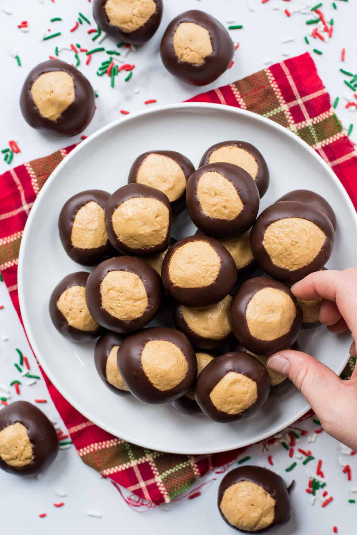 peanut butter balls on a white plate over a red striped towel on a white background