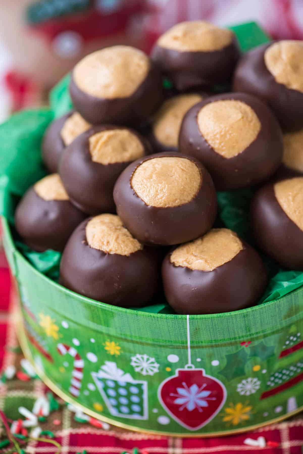 peanut butter balls in green christmas cookie tin with red striped towel under the tin