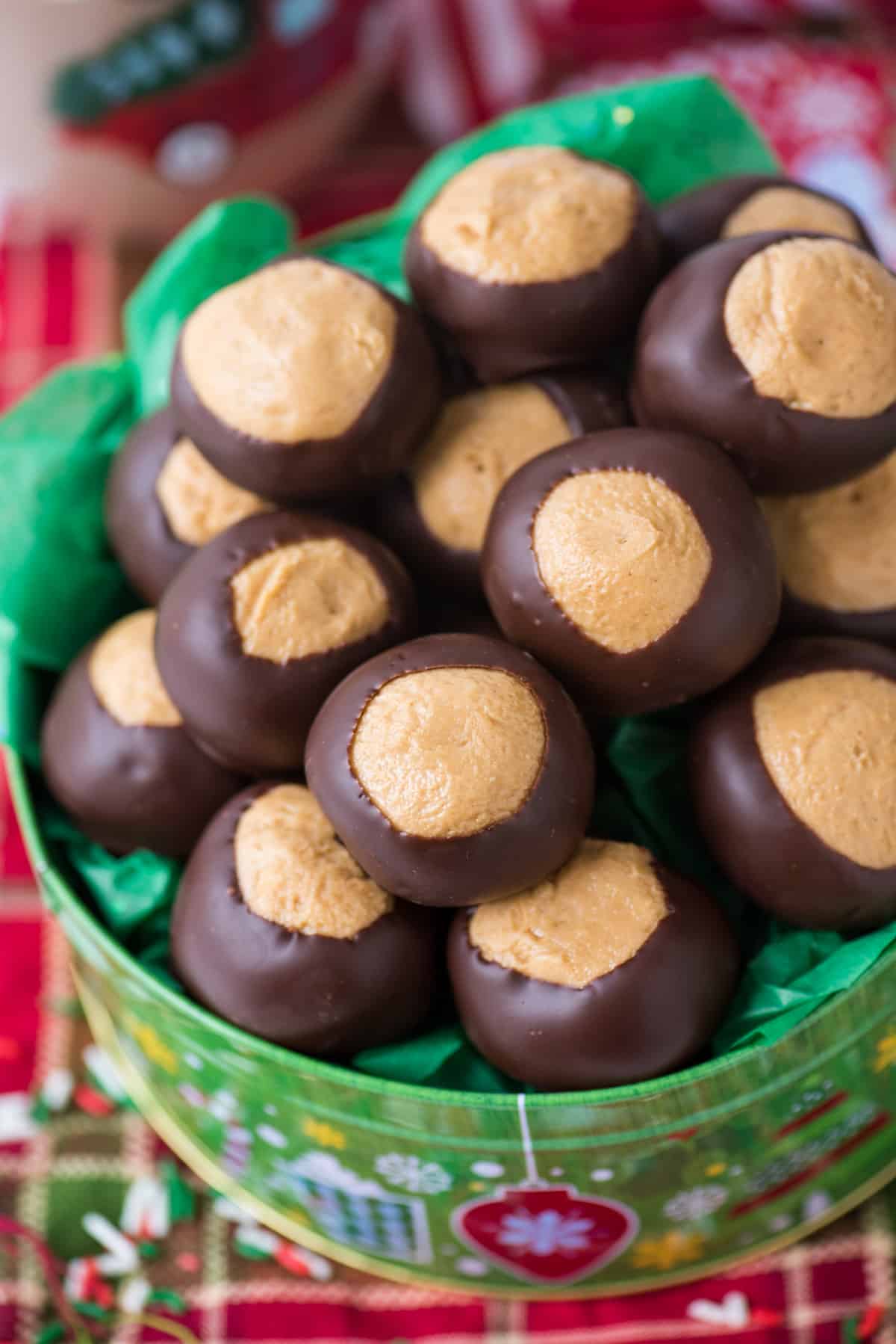 peanut butter balls in green christmas cookie tin on red striped towel background