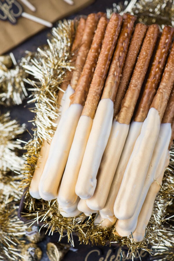 pretzel rods dipped in caramel and white chocolate and sprayed with edible gold paint to look golden and shimmery