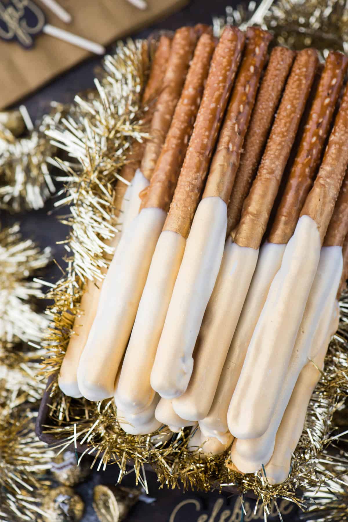 pretzel rods dipped in caramel and white chocolate and sprayed with edible gold paint to look golden and shimmery 