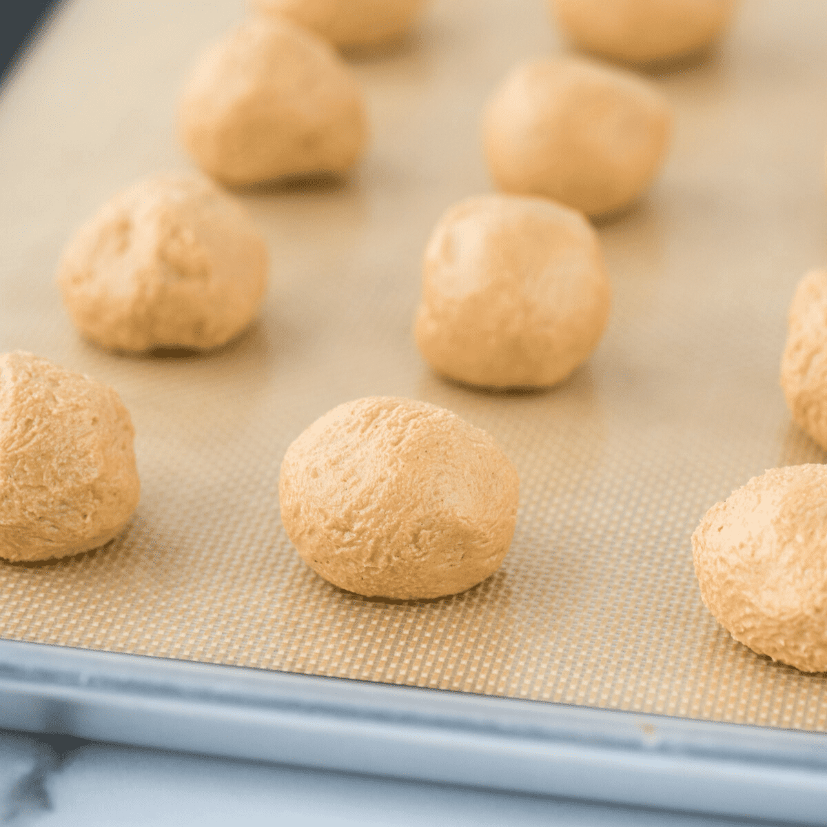 peanut butter balls arranged in grid pattern on silicone mat