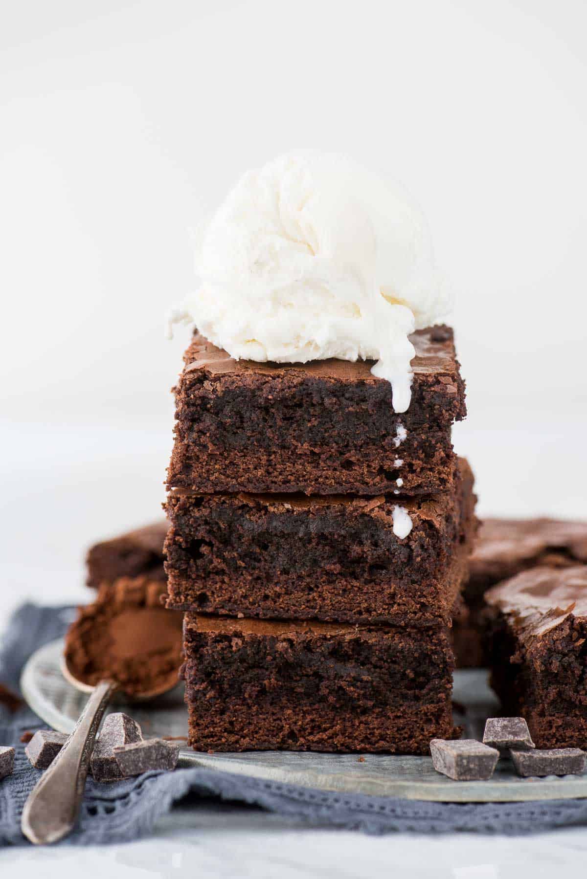 3 brownies in a stack with scoop of vanilla ice cream on top