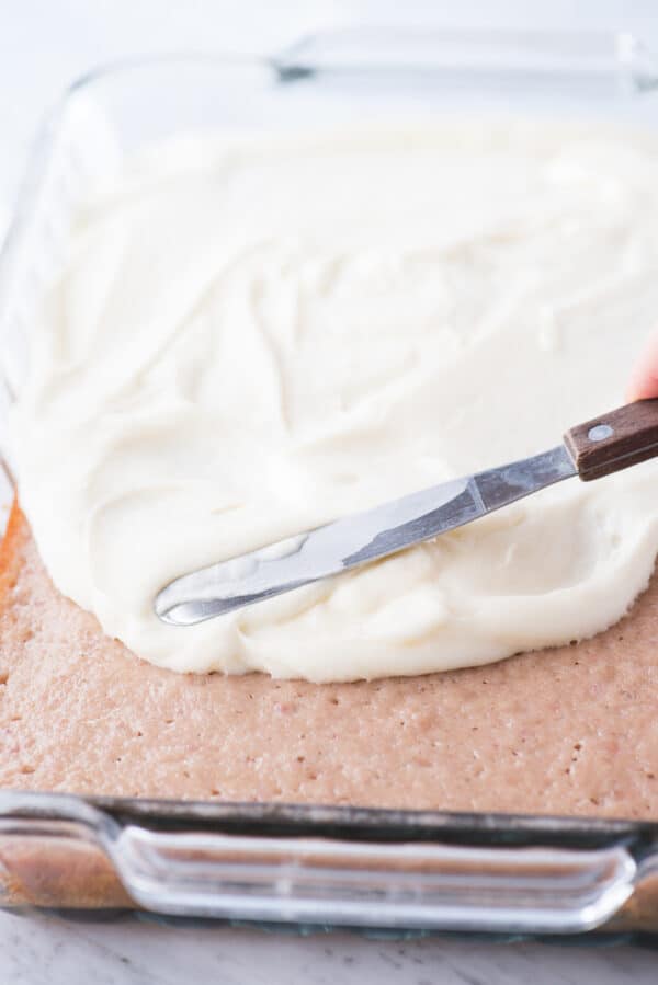 cream cheese frosting being spread onto a cake