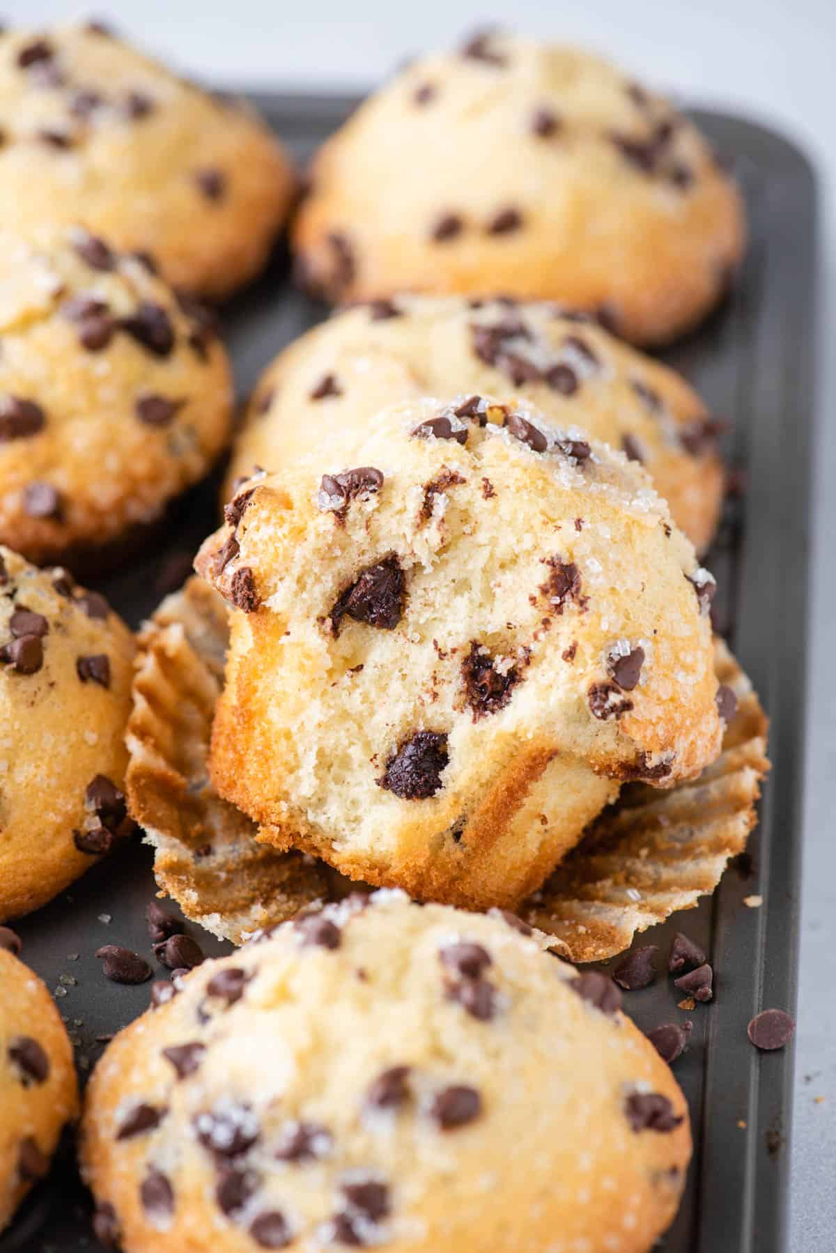 chocolate chip muffin with bite removed displayed in muffin pan