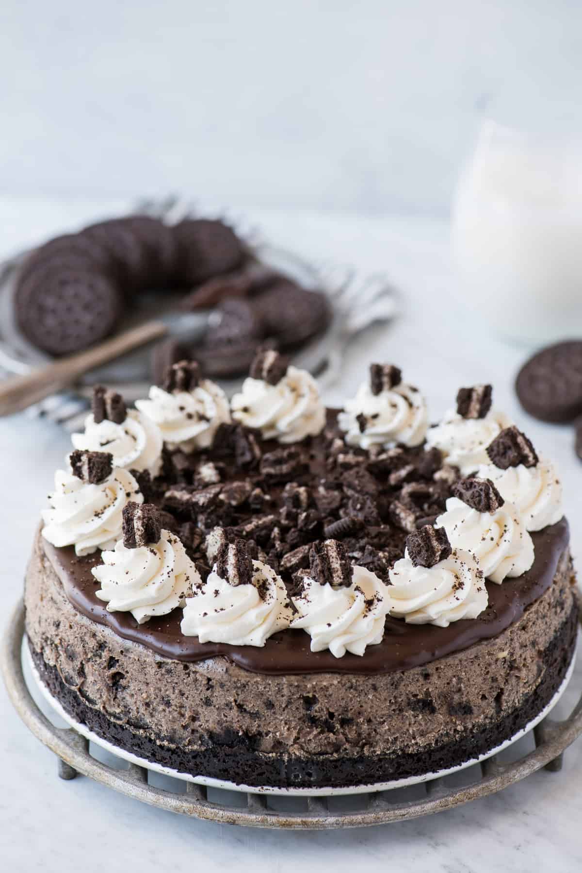 whole oreo cheesecake topped with whipped cream swirls on white background