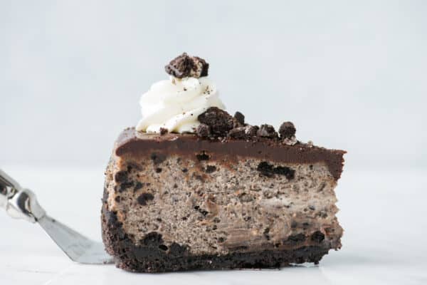 slice of oreo cheesecake on metal spatula on white background