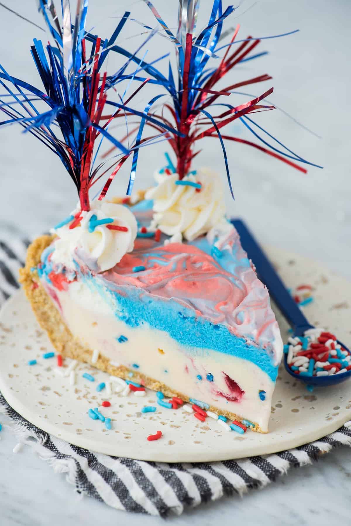 slice of 4th of july red, white and blue ice cream pie on white plate with blue stripe napkin 