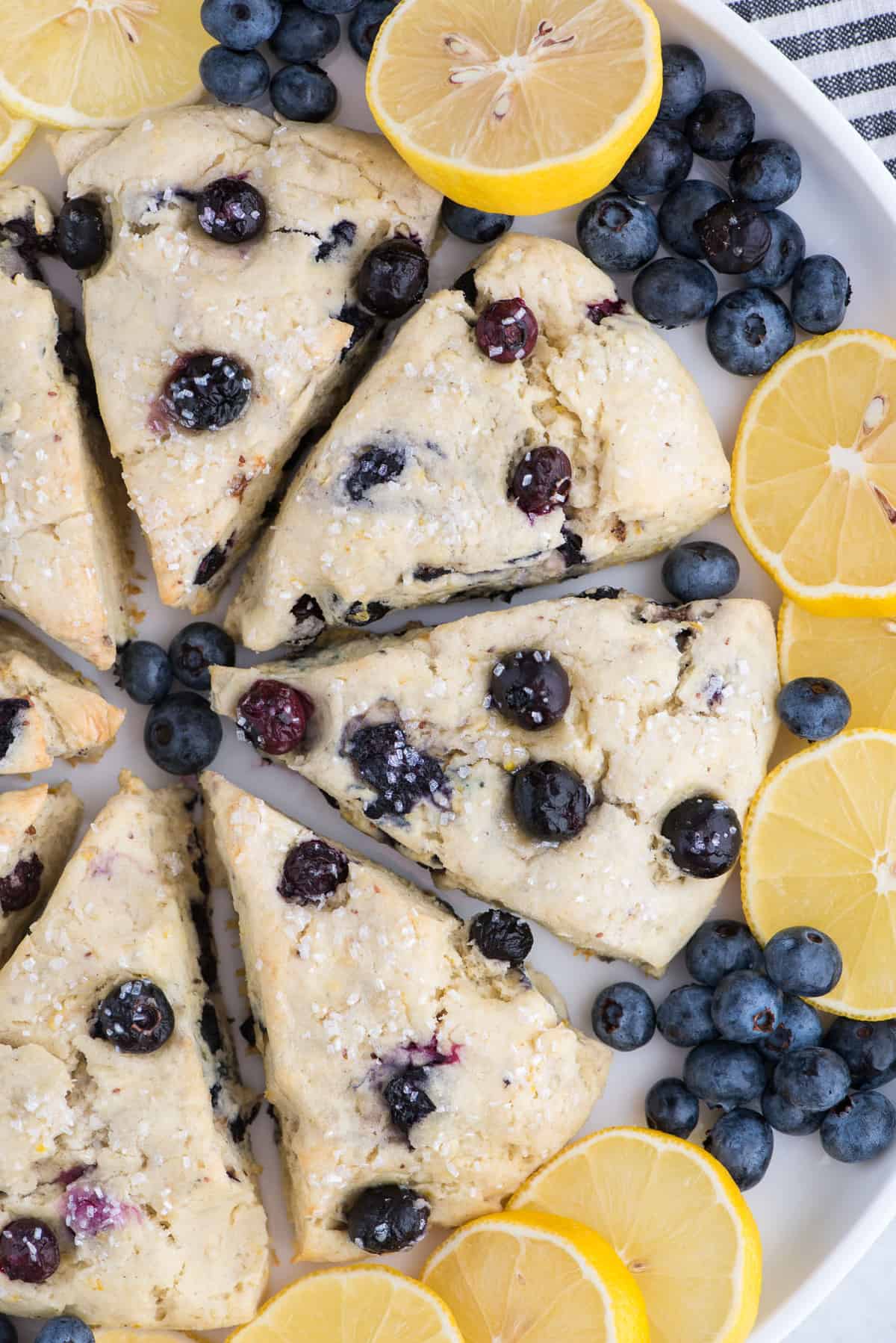lemon blueberry scones in a circle on white platter surrounded by lemon slices and blueberries