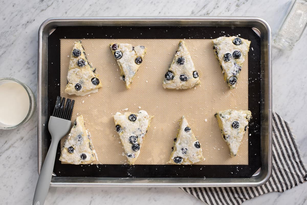 lemon blueberry scones on baking sheet with heavy cream on top