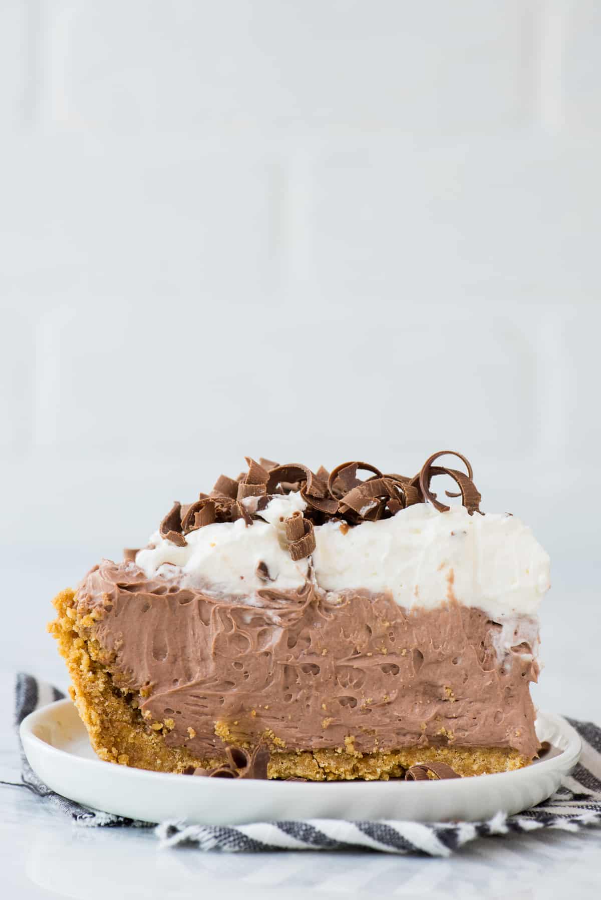 slice of chocolate pudding pie on white plate on white background