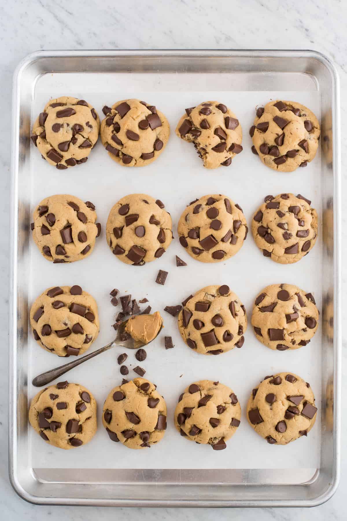 peanut butter chocolate chip cookies lined up on metal baking sheet on white background