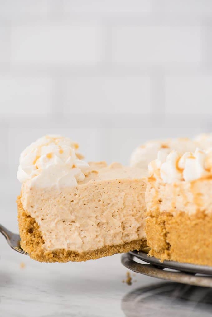 slice of pumpkin cheesecake being removed from the cheesecake on a metal spatula