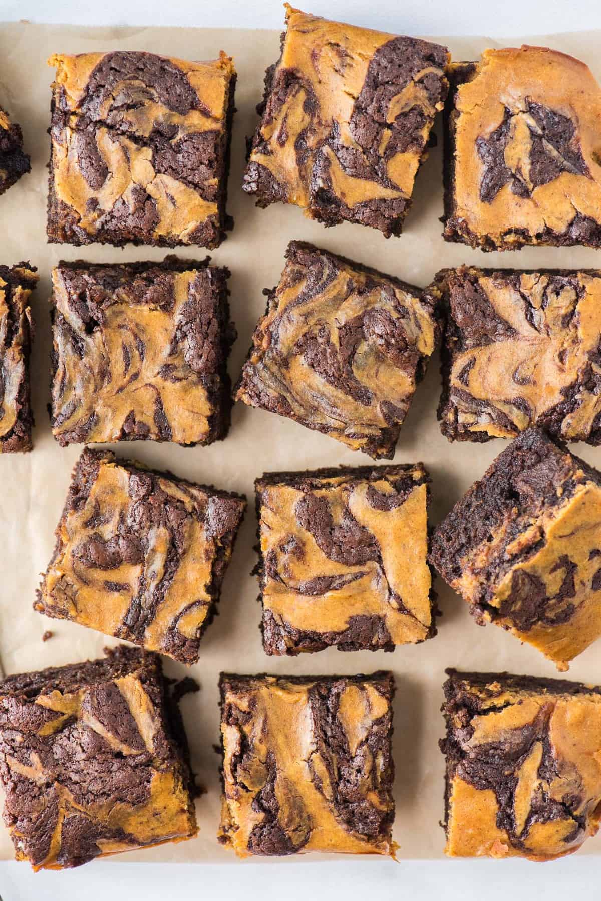 pumpkin brownies cut into 12 squares on brown parchment paper