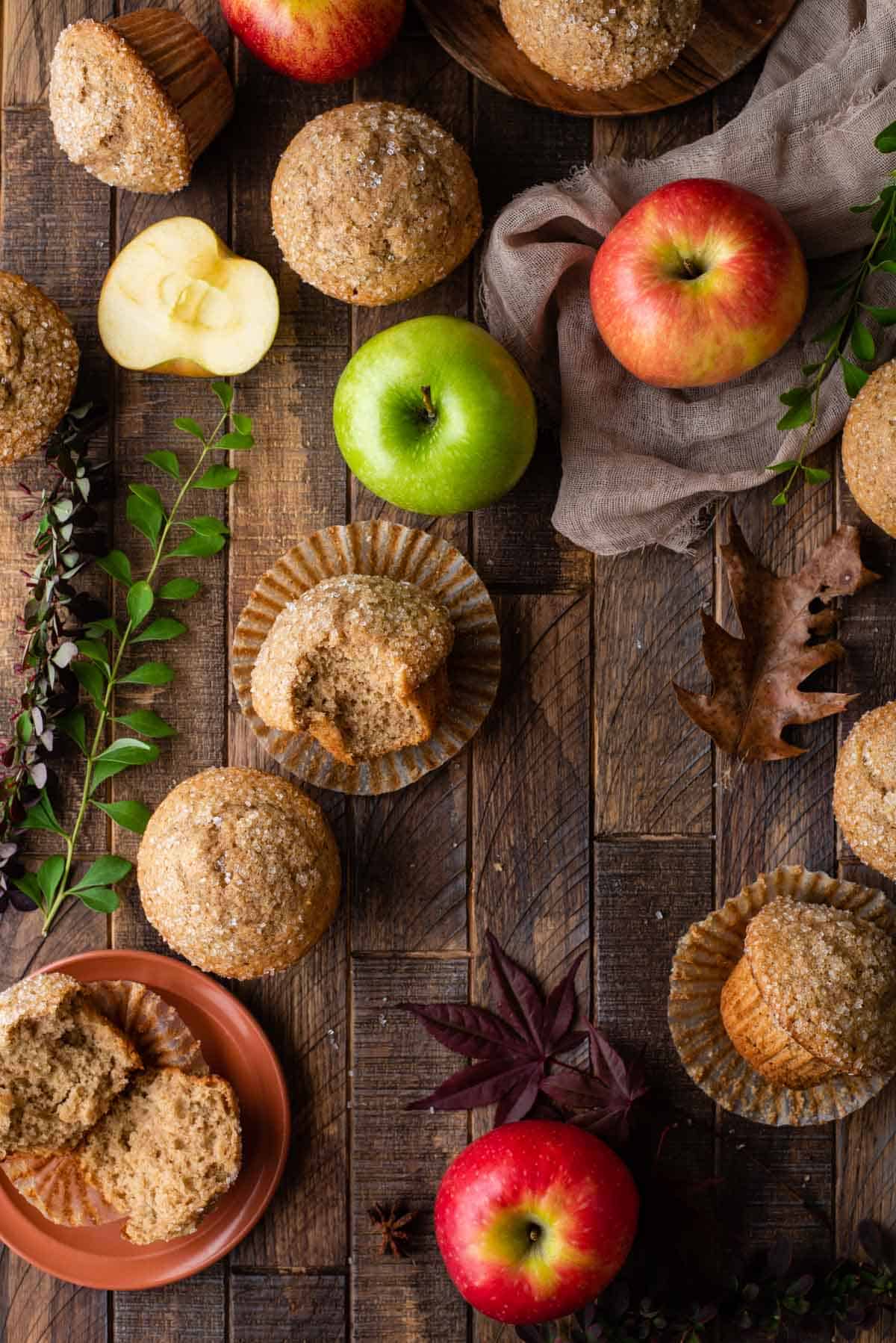 applesauce muffins arranged on wood background with apples and fall foliage 