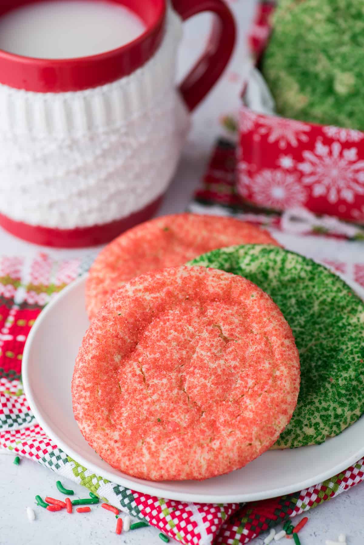 red and green christmas cookies on white plate with red mug in background