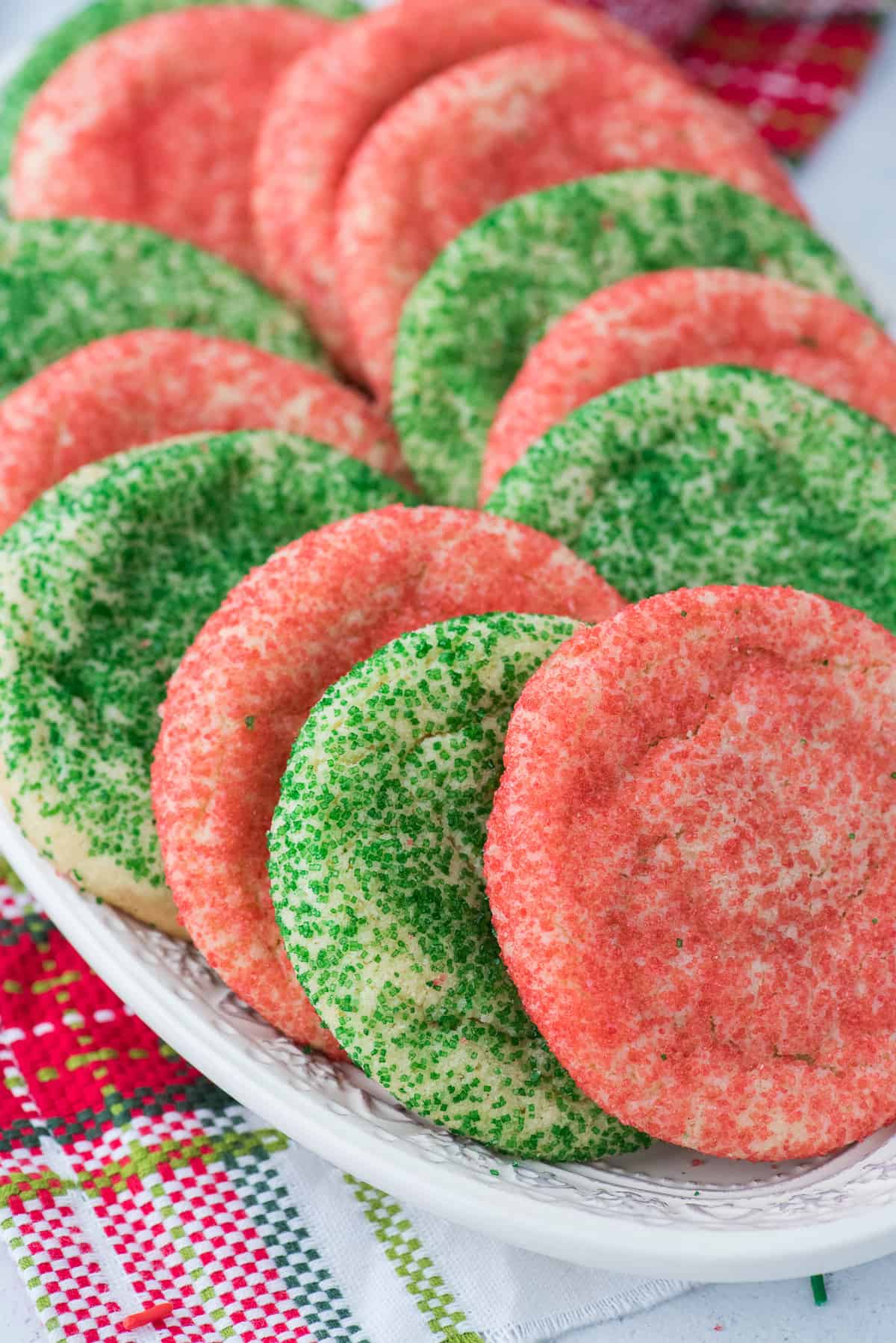 red and green sugar cookies on white plate with christmas napkin in the background
