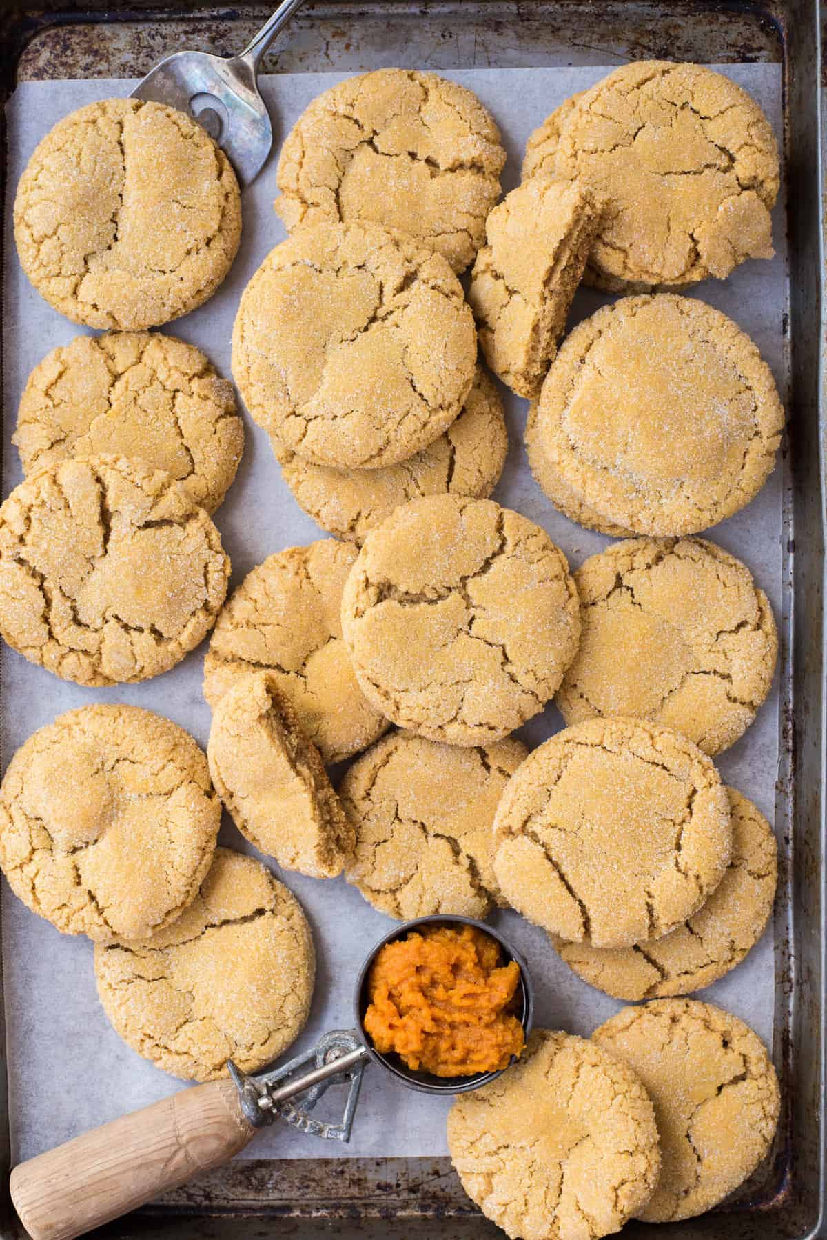 pumpkin cookies randomly arranged on metal baking sheet with white parchment paper