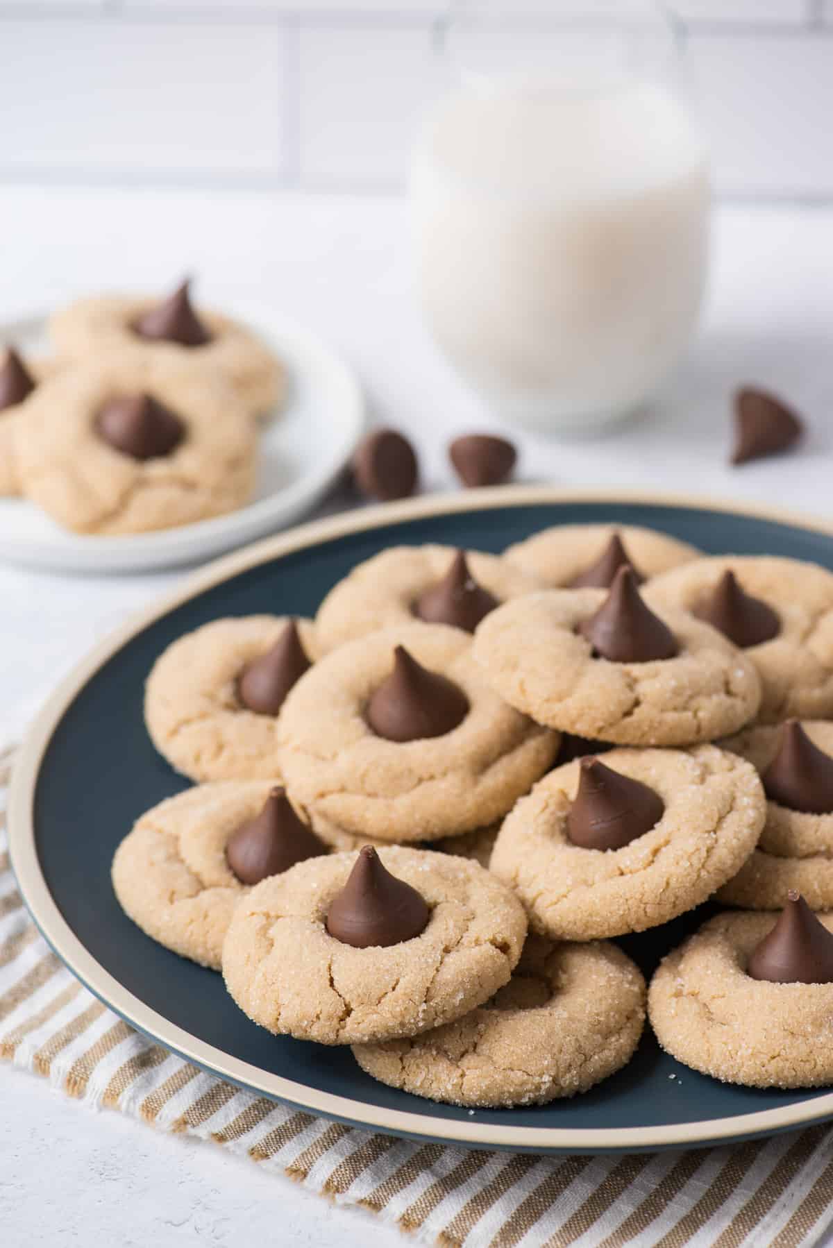 hershey kiss cookies on a blue plate with glass of milk in the background